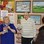 Библиотекарь Наталья Михайловна Севастьянова и Вениамин Александрович Тунгусов у книжной выставки "И не было крепче сплава, испытанного огнем". На заднем плане выставка картин местного художника Владимира Арсентьевича Первышина
